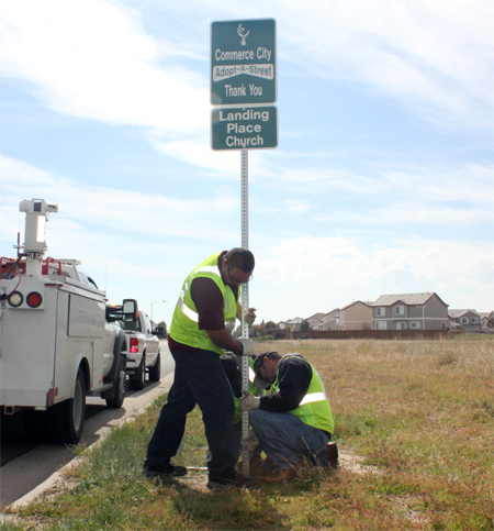 Men erecting an adopt-a-street sign
